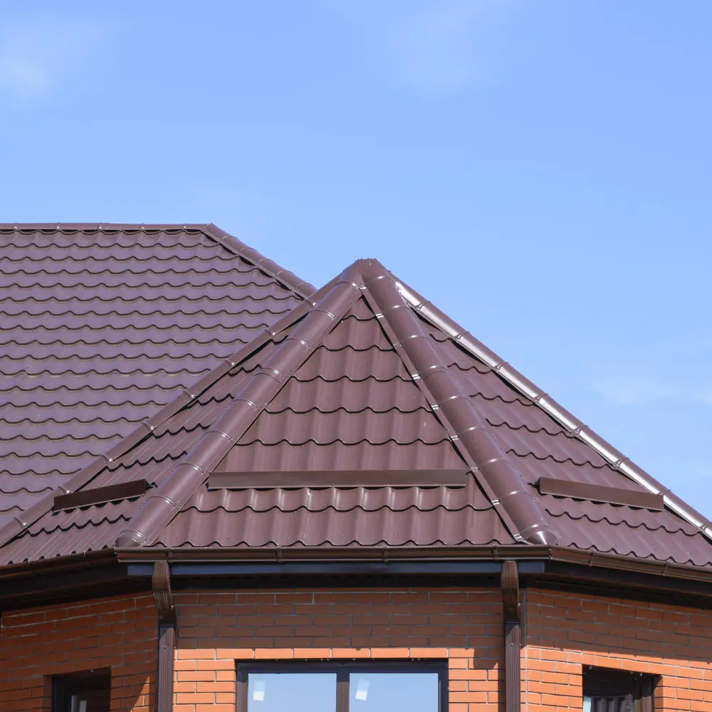 Close-up of a residential building with a brown metal roof featuring durable, wavy panels, ideal for roof services tailored to HOAs, condos, and residential associations under a clear blue sky